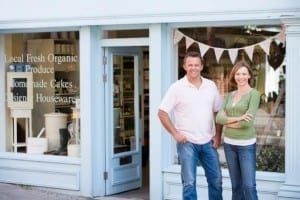 Couple posing happily outside their local small business shop.