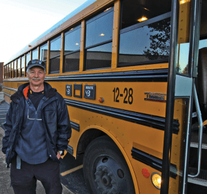 Bus driver standing by his bus.