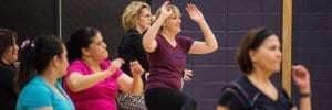 Group of teachers enjoying a dance fitness class in the gym.