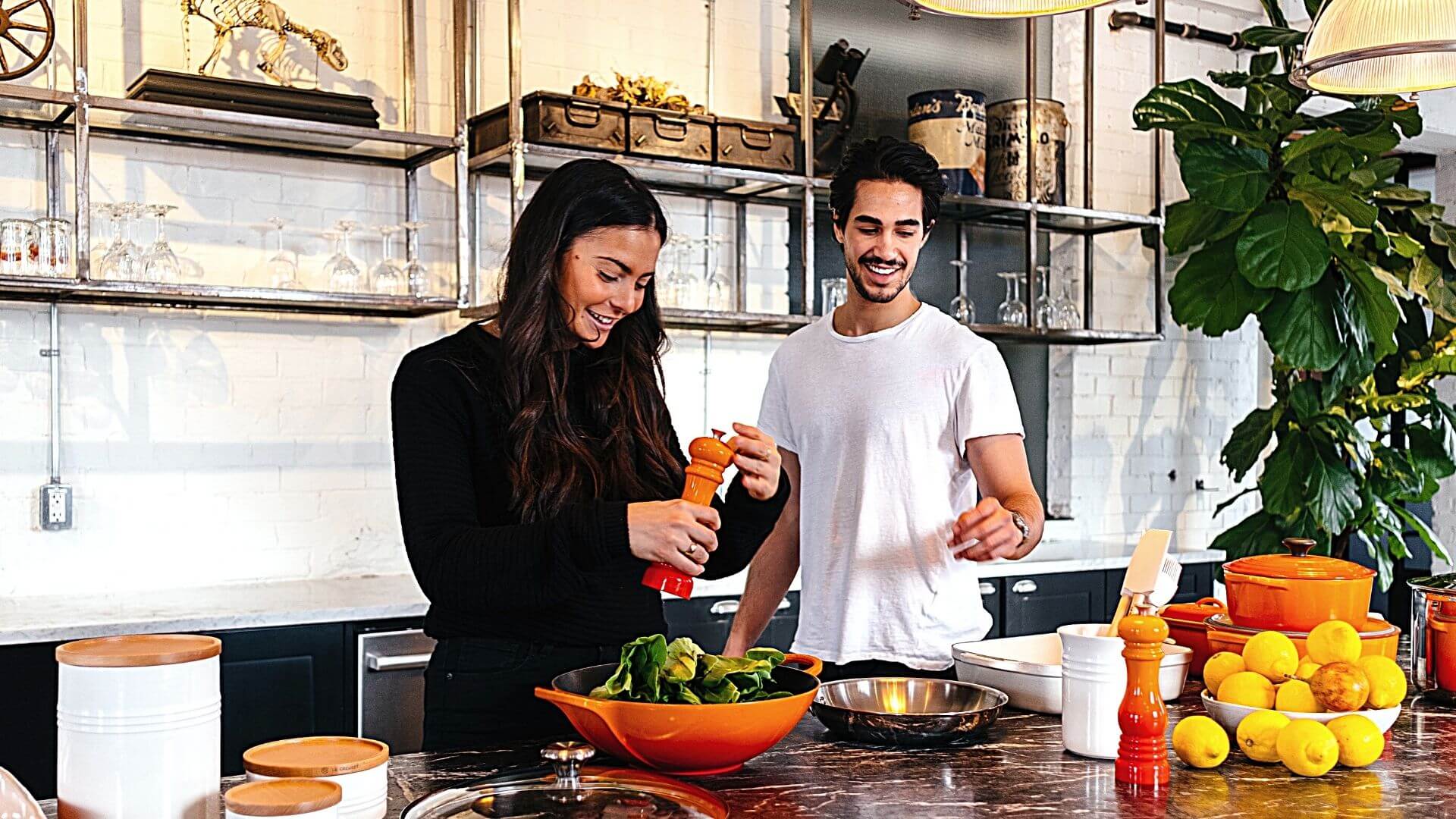 Two people preparing a salad in a large bright kitchen.