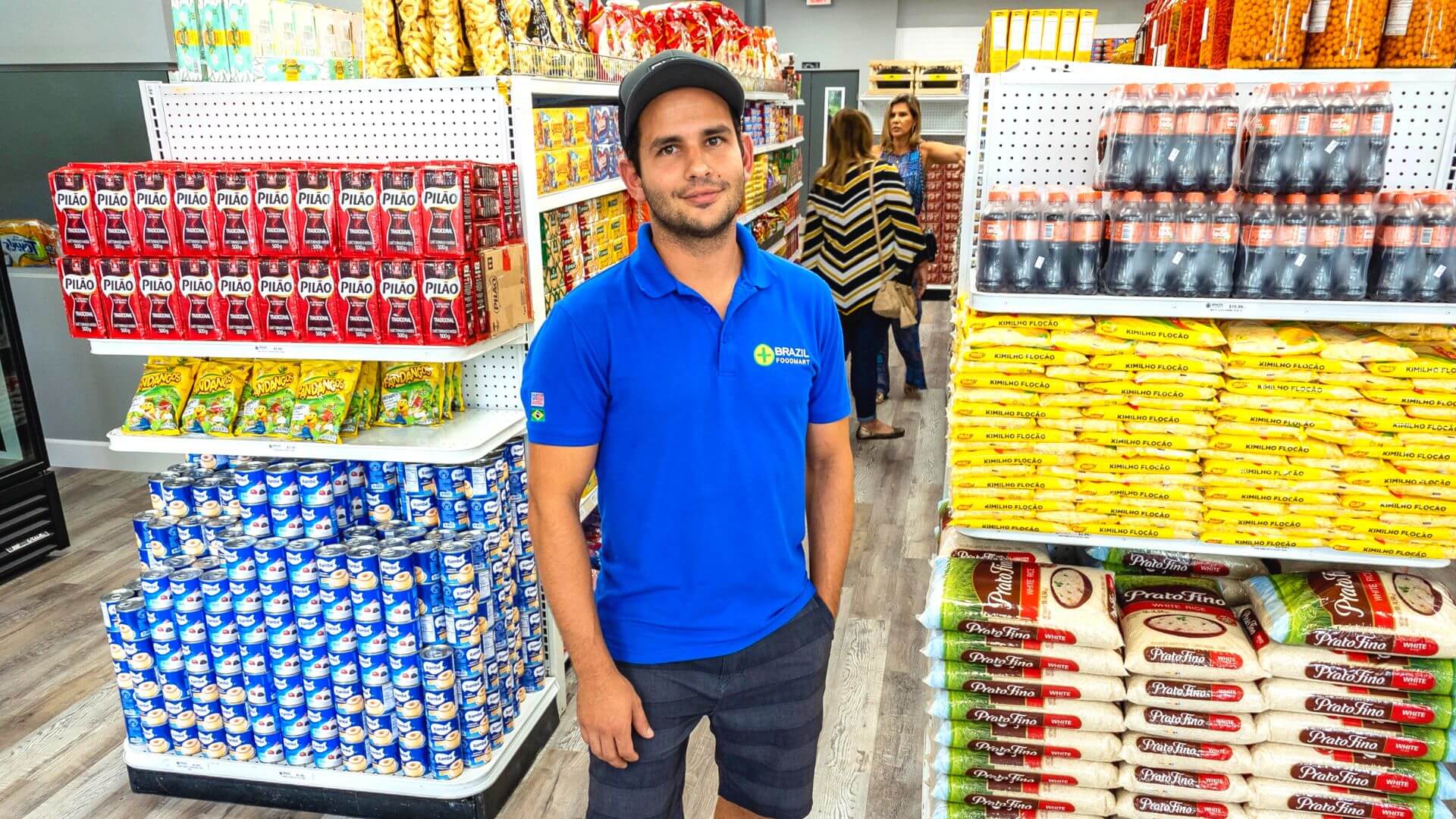 Man in blue shirt standing in a grocery store aisle.