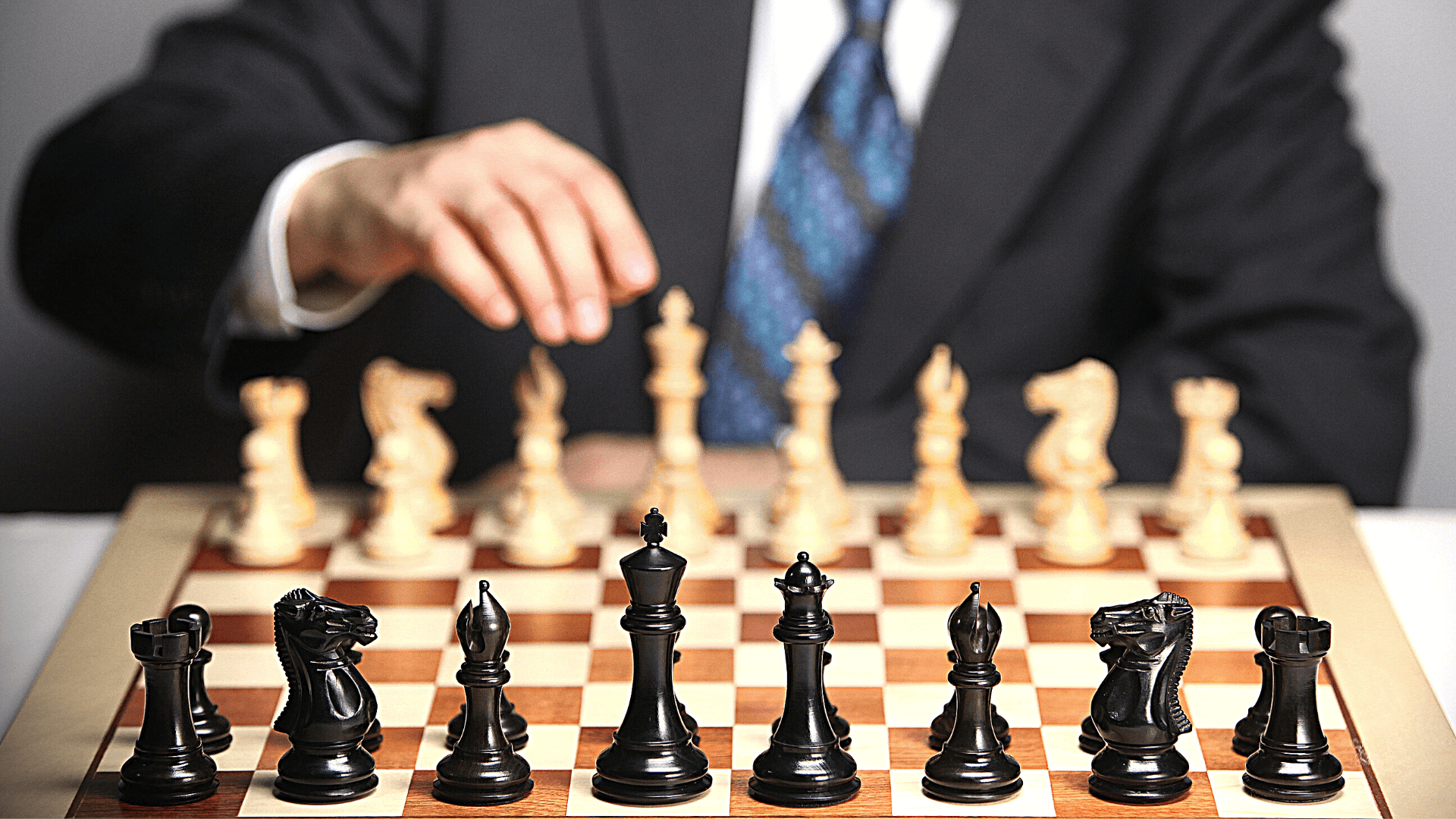 Man in black with a blue tie playing chess, from the opponents viewpoint.