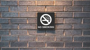 No smoking sign on a grey brick wall.