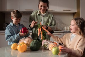 Family unloading fruits and vegetables from a reusable bag in their kitchen.