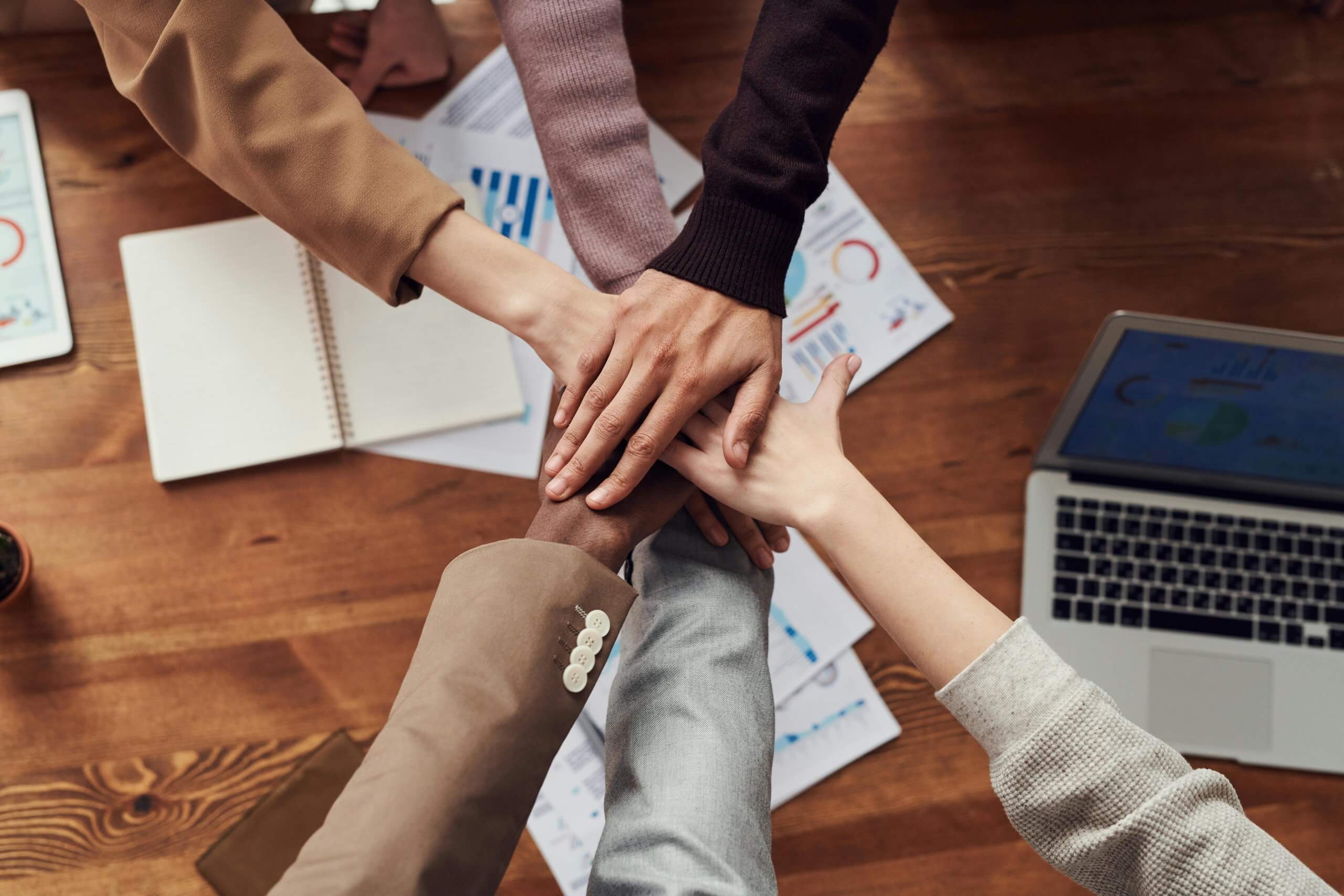 Employees putting hands together in celebration after a successful DEI meeting.